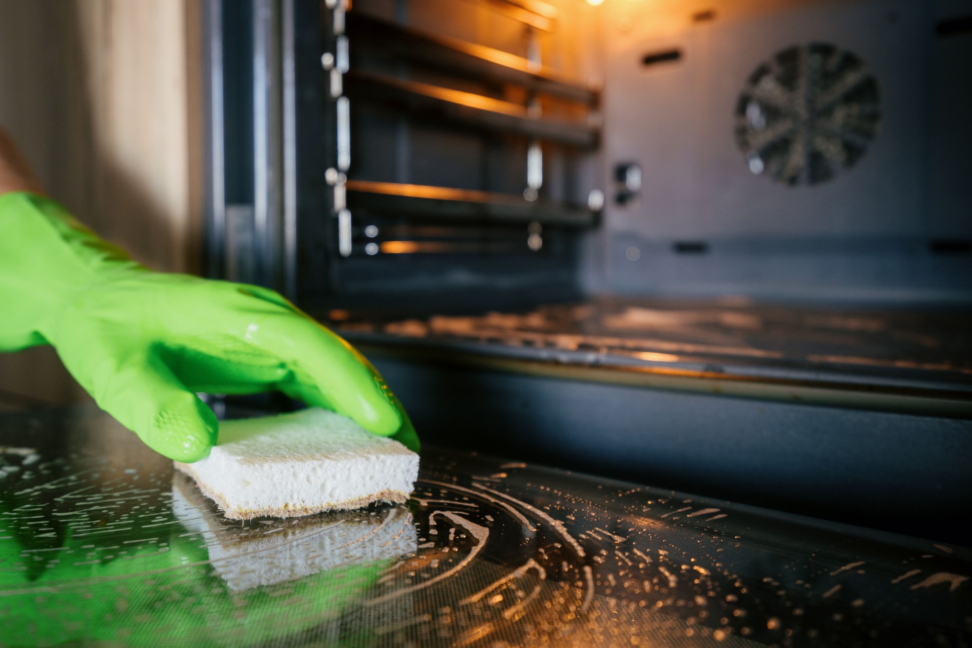 Woman using sponge to clean modern oven in a stylish kitchen