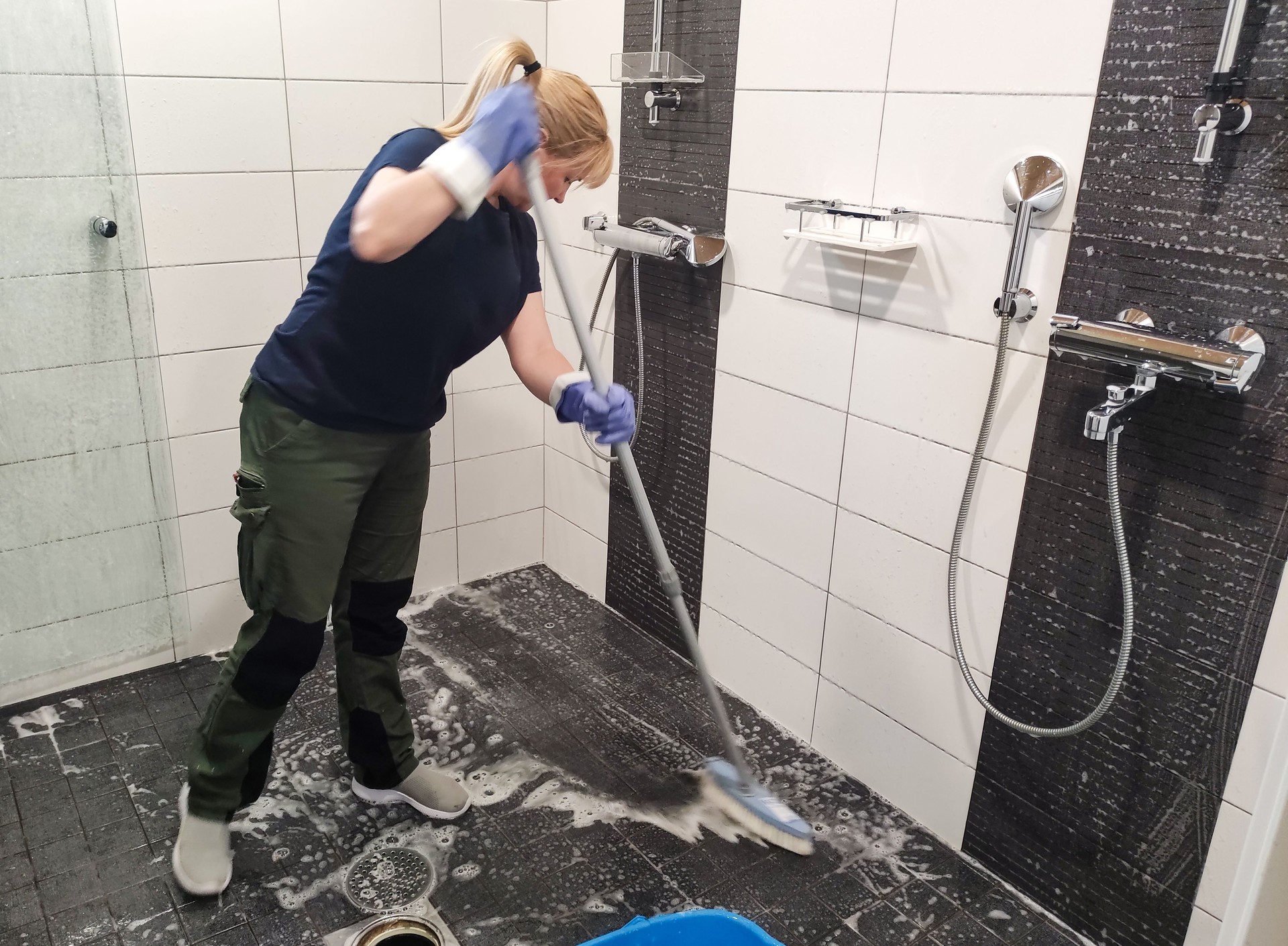 Caucasian woman, 45 years old, washes the tiled floor in the shower.